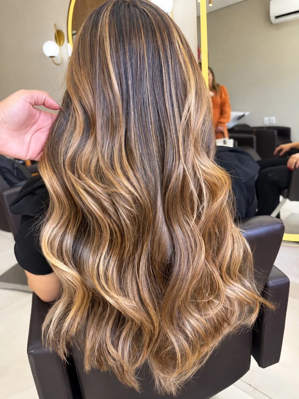 Cabelos longos vistos de trás, com mechas douradas e ondas